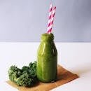 Energizing green smoothie with kale, served in a bottle with vibrant straws for a healthy lifestyle.